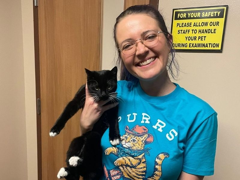 a vet staff cradles a cat in her arms